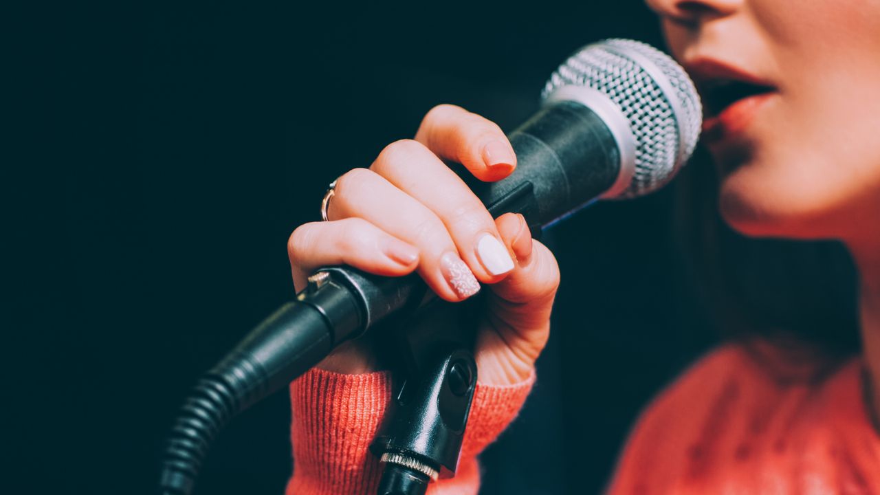 A singer singing into a microphone with the help of the Voice Straw and Cup